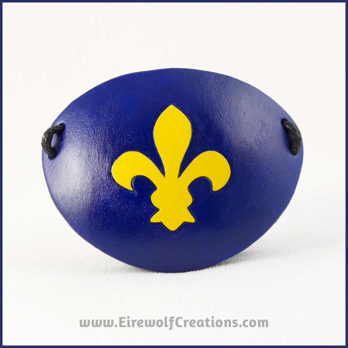 A handmade leather eye patch with a carved Fleur de Lis symbol, bright yellow on a dark blue background. By Erin Metcalf of Eirewolf Creations.