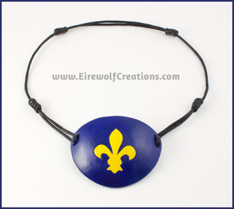 A handmade leather eye patch with a carved Fleur de Lis symbol, bright yellow on a dark blue background. By Erin Metcalf of Eirewolf Creations.