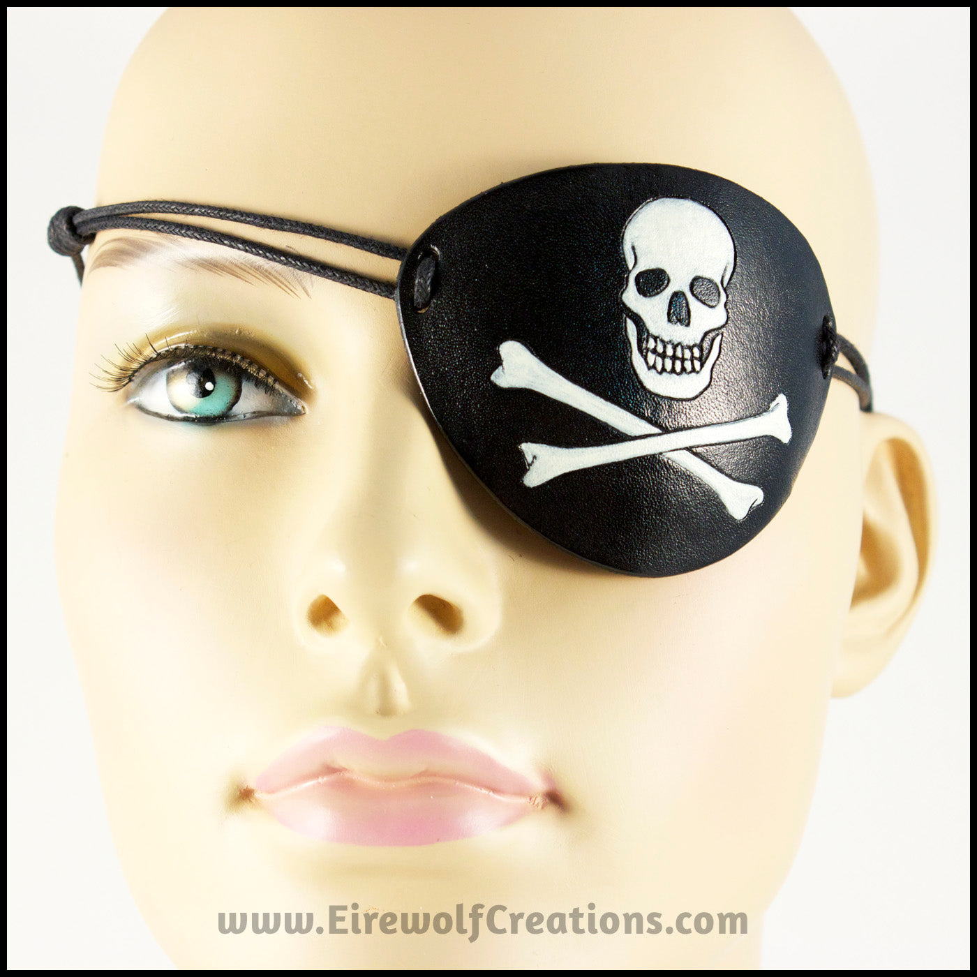 A handmade leather Jolly Roger eye patch, with hand carved and painted skull and bones, for a masquerade costume or pirate cosplay. By Erin Metcalf of Eirewolf Creations.