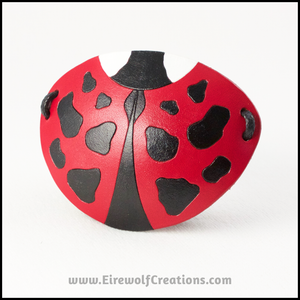 A cute handmade leather Ladybug eye patch, carved and painted red, black, and white. By Erin Metcalf of Eirewolf Creations.