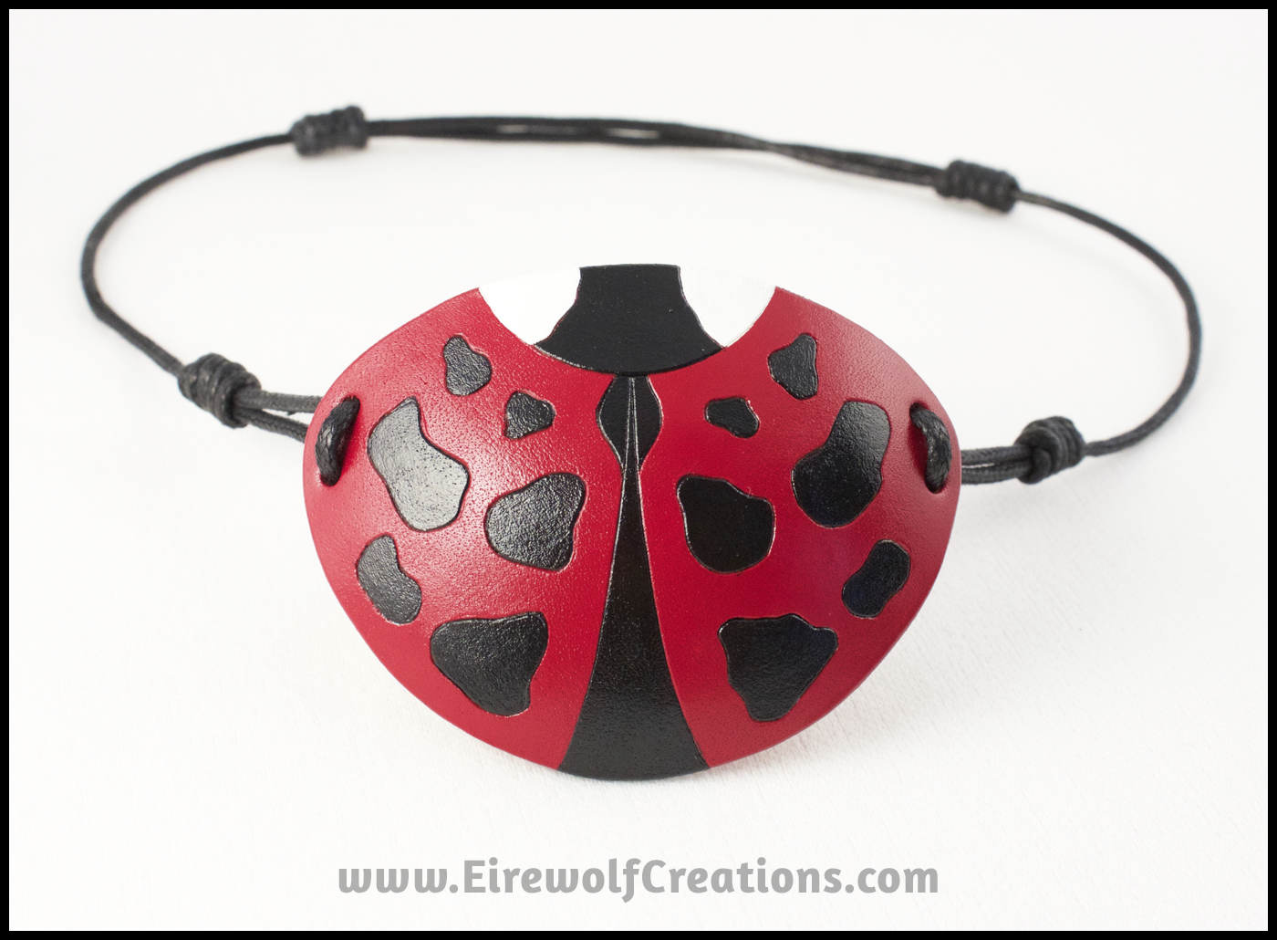 A cute handmade leather Ladybug eye patch, carved and painted red, black, and white. By Erin Metcalf of Eirewolf Creations.