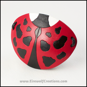 A cute handmade leather Ladybug eye patch, carved and painted red, black, and white. By Erin Metcalf of Eirewolf Creations.