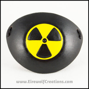 A handmade leather eye patch with a carved and painted radiation hazard symbol in black and yellow, for a masquerade costume or pirate cosplay. By Erin Metcalf of Eirewolf Creations.