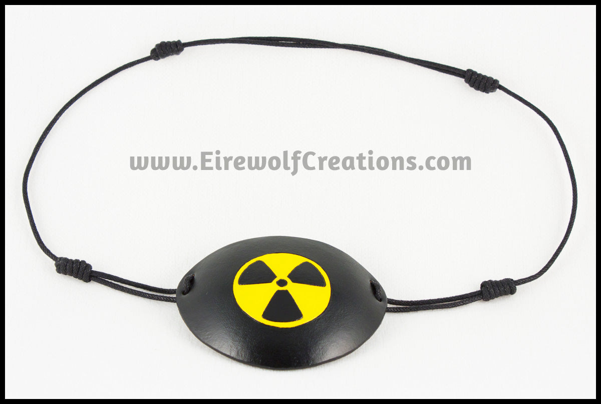 A handmade leather eye patch with a carved and painted radiation hazard symbol in black and yellow, for a masquerade costume or pirate cosplay. By Erin Metcalf of Eirewolf Creations.