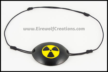 A handmade leather eye patch with a carved and painted radiation hazard symbol in black and yellow, for a masquerade costume or pirate cosplay. By Erin Metcalf of Eirewolf Creations.