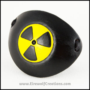 A handmade leather eye patch with a carved and painted radiation hazard symbol in black and yellow, for a masquerade costume or pirate cosplay. By Erin Metcalf of Eirewolf Creations.