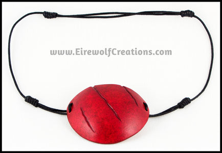 A handmade leather eye patch with three jagged scars carved diagonally, dyed and painted a mottled red reminiscent of blood, for a masquerade costume or assassin or pirate cosplay. By Erin Metcalf of Eirewolf Creations.