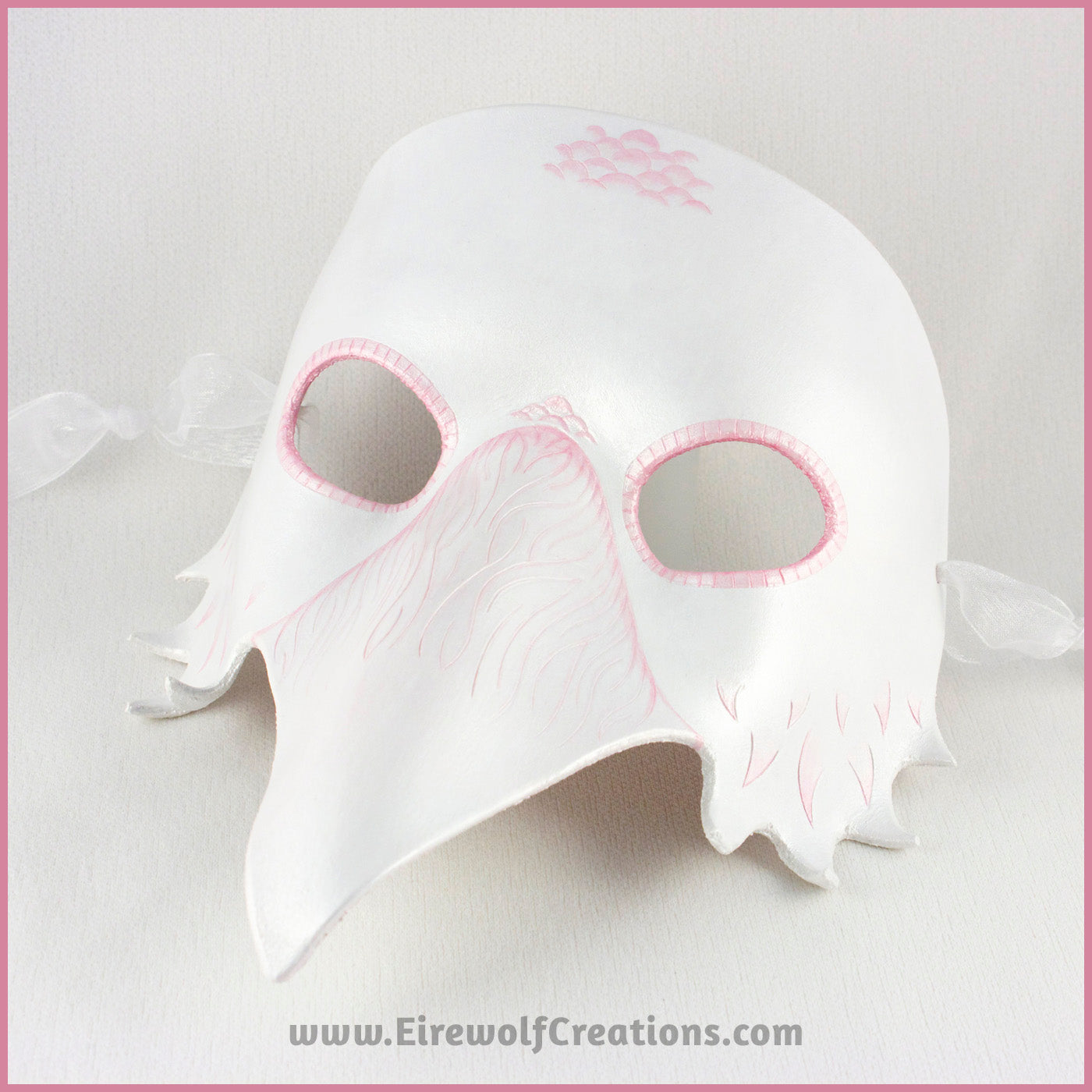 A handmade leather Albino Raven or White Crow mask for a masquerade costume, with carved and handpainted pale pink feather details. By Erin Metcalf of Eirewolf Creations.