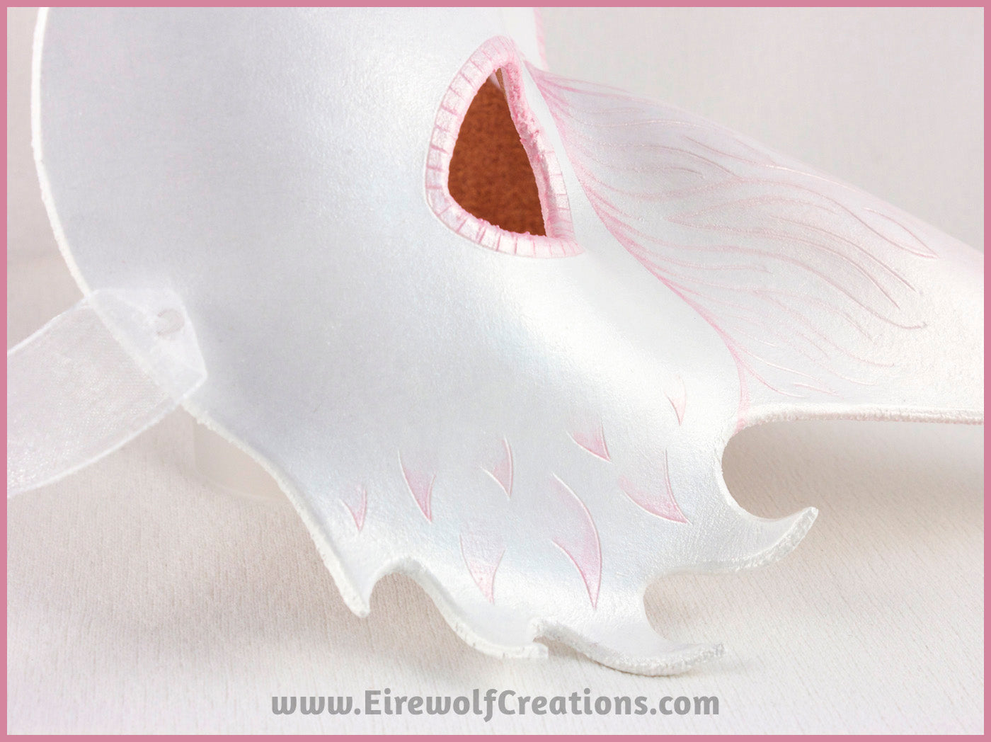 Detail of A handmade leather Albino Raven or White Crow mask for a masquerade costume, with carved and handpainted pale pink feather details. By Erin Metcalf of Eirewolf Creations.