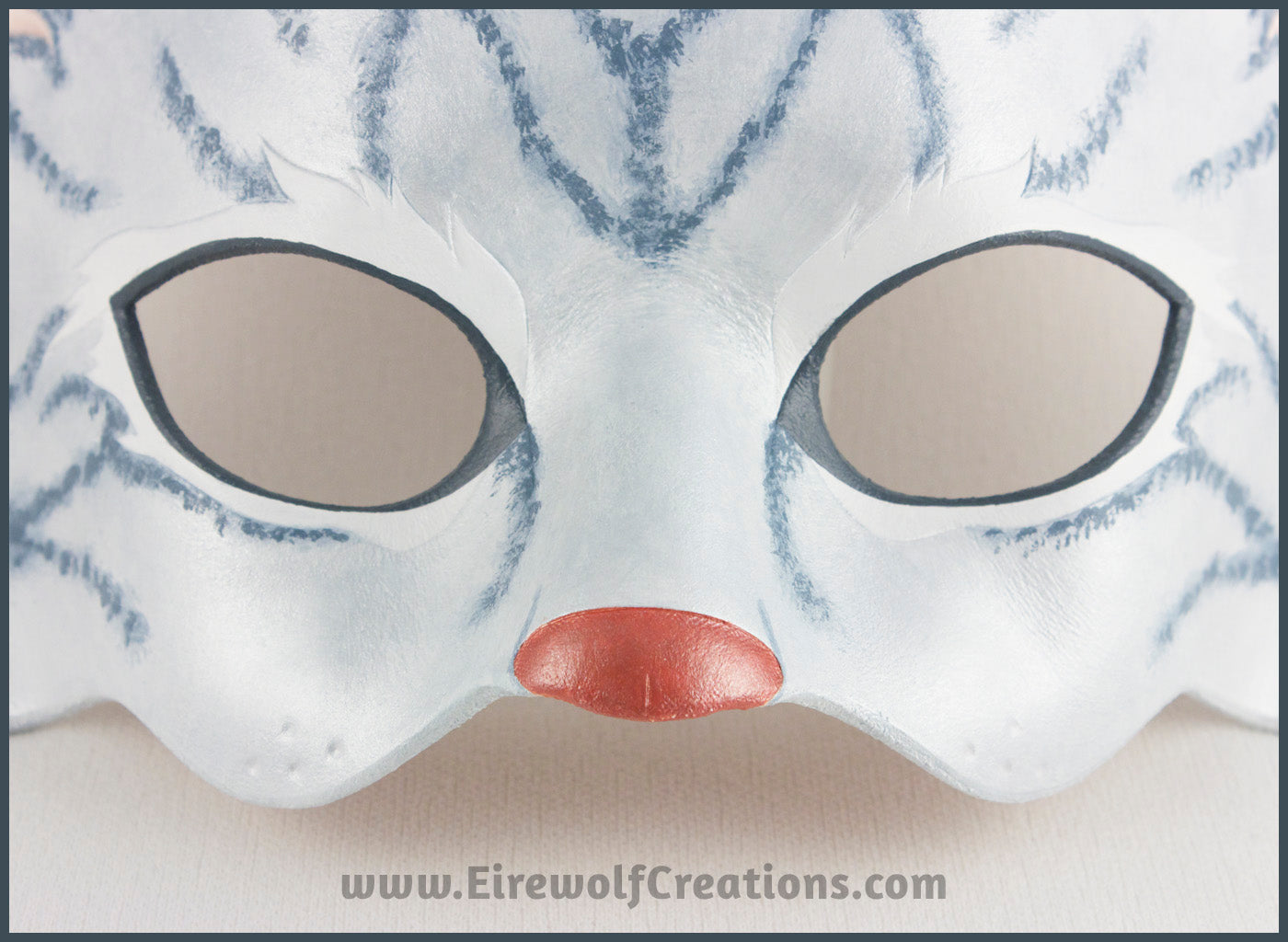 Detail of a handmade leather silver-gray tabby cat mask for a masquerade costume, with handpainted stripes, a dark pink nose and light pink inner ears. By Erin Metcalf of Eirewolf Creations.