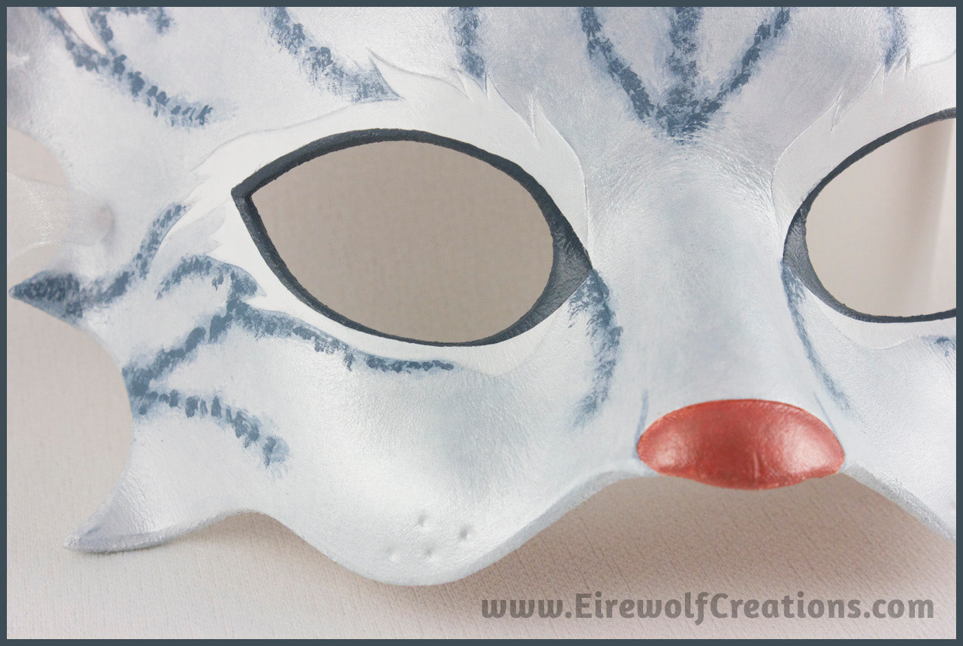 Detail of a handmade leather silver-gray tabby cat mask for a masquerade costume, with handpainted stripes, a dark pink nose and light pink inner ears. By Erin Metcalf of Eirewolf Creations.