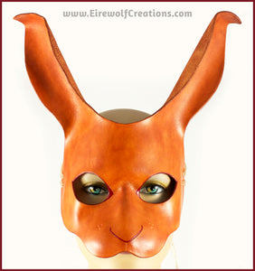 A handmade leather rabbit mask for a masquerade costume, dyed light brown with subtle red details painted around the eyes and nose. By Erin Metcalf of Eirewolf Creations.