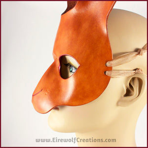 Closeup of a handmade leather rabbit mask for a masquerade costume, dyed light brown with subtle red details painted around the eyes and nose. By Erin Metcalf of Eirewolf Creations.