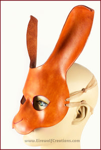 A handmade leather rabbit mask for a masquerade costume, dyed light brown with subtle red details painted around the eyes and nose. By Erin Metcalf of Eirewolf Creations.