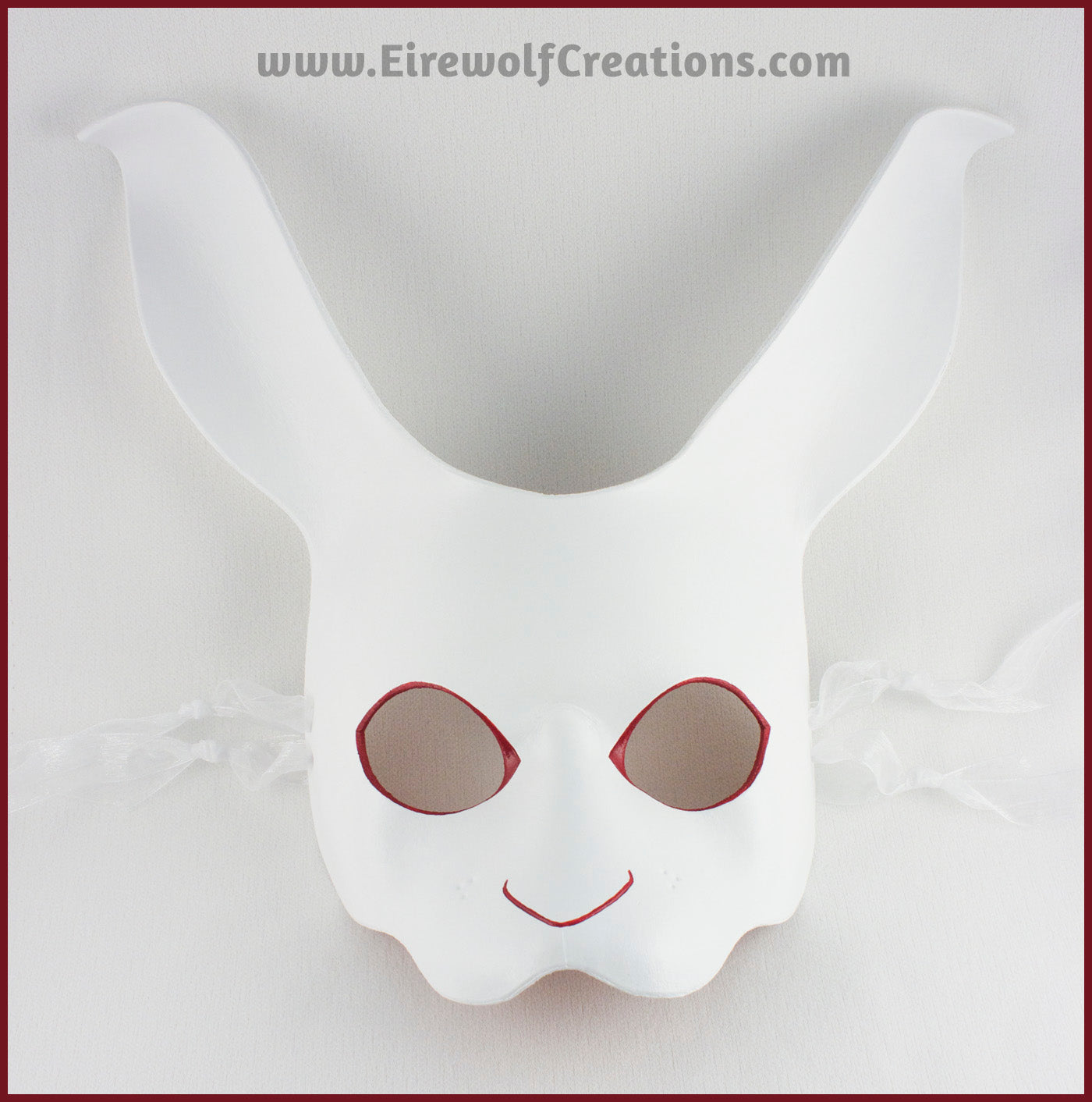 A handmade leather White Rabbit mask for a masquerade or Alice in Wonderland costume, painted white with red details around the eyes and nose. By Erin Metcalf of Eirewolf Creations.