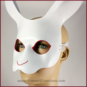 A handmade leather White Rabbit mask for a masquerade or Alice in Wonderland costume, painted white with red details around the eyes and nose. By Erin Metcalf of Eirewolf Creations.