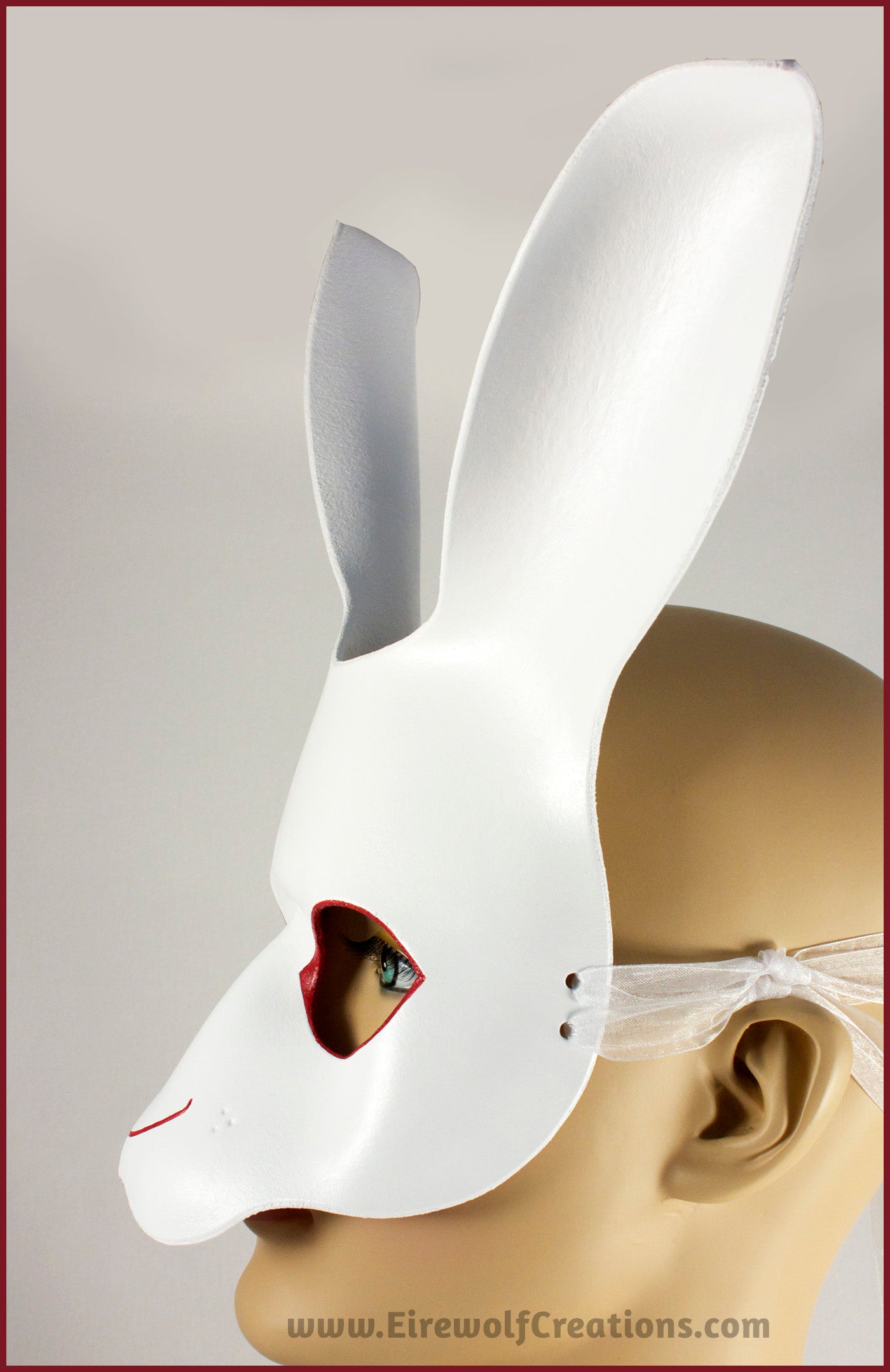 A handmade leather White Rabbit mask for a masquerade or Alice in Wonderland costume, painted white with red details around the eyes and nose. By Erin Metcalf of Eirewolf Creations.