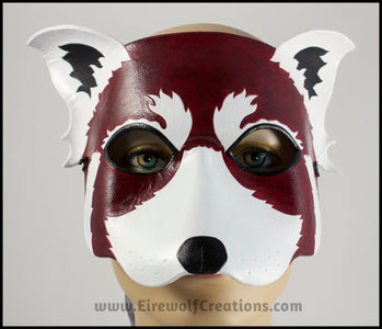 A handmade leather Red Panda masquerade mask with bold facial markings carved and painted on the leather. By Erin Metcalf of Eirewolf Creations.